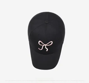Détail de la broderie nœud rose sur casquette de baseball en coton noir, vue de haut