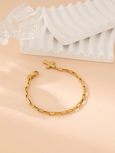 Close-up of a minimalist golden stainless steel bracelet with a cross pendant charm