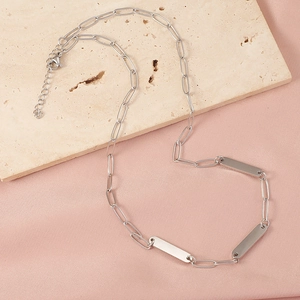 Minimalist silver bar pendant necklace with paperclip chain on stone background