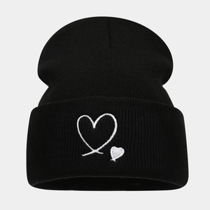 Close-up of heart embroidery on black knit beanie showing soft fabric texture