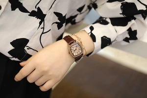 Detailed view of women's vintage square gold watch with crystal bezel and brown leather strap