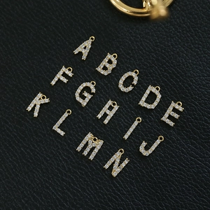 Macro shot of 18k gold plated alphabet letter charms with cubic zirconia on black leather