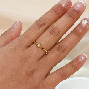 Close-up of a 18K gold-plated beaded ring with a sparkling round zircon on finger