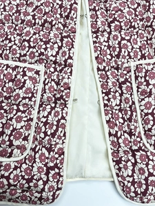 Detail of vintage quilted floral cotton coat with metal hooks and pocket piping