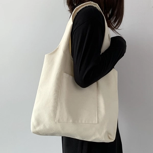 Detail shot of a minimalist off-white canvas tote bag featuring a spacious front pocket