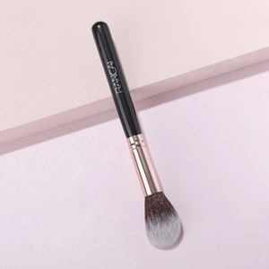 Detail of soft tapered powder brush with rose gold ferrule and sparkling black wood handle