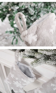 Close-up of grey plush Christmas stocking with white snowflake and hanging loop detail