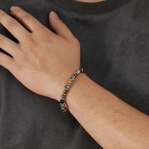 Nahaufnahme eines Tigerauge-Hämatit-Armbands am Handgelenk eines Mannes
