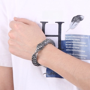 Macro shot of a punk-style eagle head bangle with vintage silver finish on a male wrist