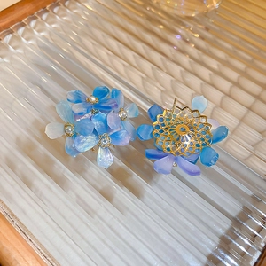 Macro shot of blue gradient acrylic flower earrings with golden metal filigree back detail