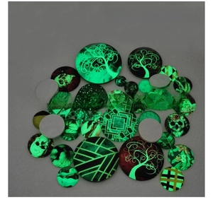 Luminous glass cabochons showing glowing tree of life and skull patterns in the dark
