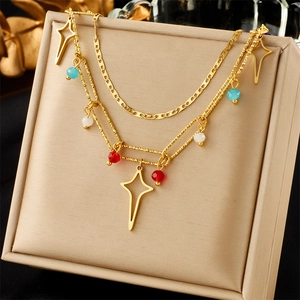 Detail of layered gold necklace with colorful beads and hollow star-shaped pendants