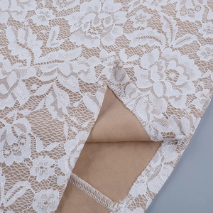 Detailed view of floral white lace fabric with beige lining and quality stitching