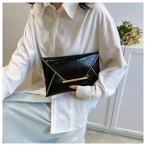 Detail of black crocodile texture envelope clutch bag with gold metallic edge accents