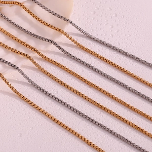 Detail view of 18K gold and silver box chains with polished finish on white background