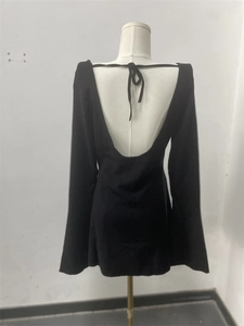 Detail of elegant black long-sleeve dress with backless U-shape and tie-neck detail