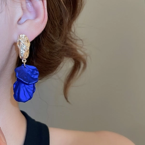 Detail of gold hammered metal stud earrings with dark blue petal tassels on model