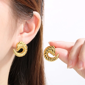 Golden irregular spiral croissant earrings with metallic texture shown on model