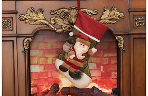 Close-up of 3D Santa Claus plush on a red Christmas stocking by a cozy fireplace