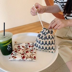 Detail of floral and geometric fabric drawstring storage bags on a white tray