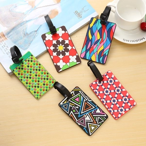 Five assorted colorful PVC luggage tags with adjustable straps on a light wooden background
