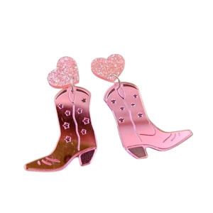 Detailed view of pink acrylic cowboy boot earrings with glitter heart and star motifs