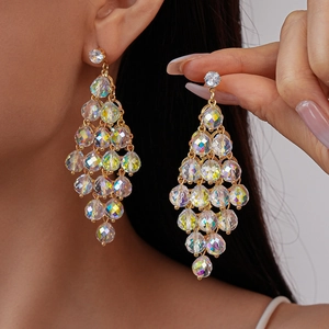 Close-up of gold dangle earrings with faceted colorful crystals worn by a model
