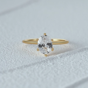 Detailed close-up of a luxury oval-cut gemstone set in a gold six-prong minimalist ring