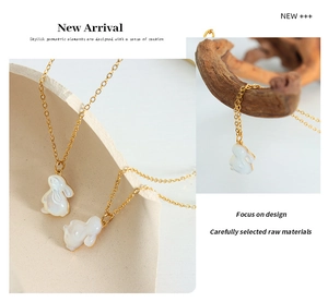 Gros plan d'un collier en chaîne dorée avec un pendentif lapin blanc 3D sur céramique