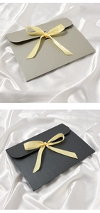 Gray and black envelope gift boxes with yellow silk ribbons on white silk background