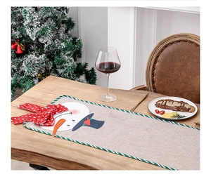 Detail of Christmas burlap table runner featuring a snowman applique and festive striped edge