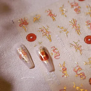 Détail d'autocollants 3D pour ongles dorés avec motifs de dragon rouge et bambou