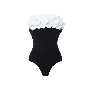 Detail of a one-piece swimsuit featuring 3D white floral petals on a black tube top bodice