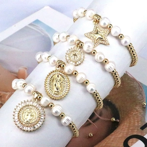 Macro shot of pearl bracelet set featuring zircon star and religious medals pendants
