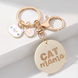 Porte-clés CAT MAMA doré avec breloque chat et pendentif M rose sur support blanc