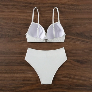 Detailed view of white ribbed bikini with wired top and high-waisted bottoms on wood