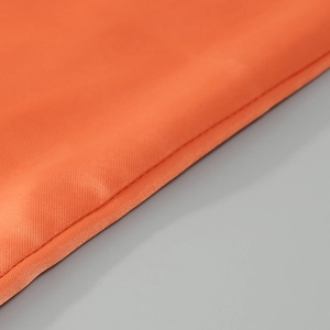 Close-up of bright orange satin fabric texture with elegant folds and glossy finish