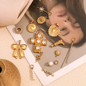 Detailed macro view of 18K gold-plated charms including Mama letters, bow and pearls