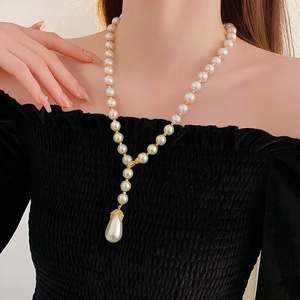 Close-up of elegant pearl necklace with gold links and teardrop pearl pendant on neck