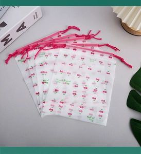 Macro shot of frosted cherry print drawstring bags with red ties on a lifestyle background