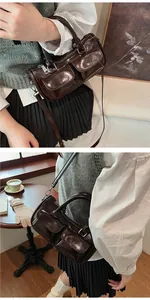 Detail of dark brown glossy patent leather saddle bag with dual front zipper pockets