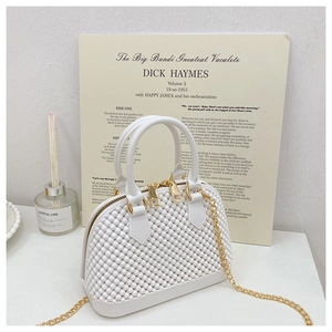 Close-up of white pearl-textured shell bag with gold hardware and chain strap