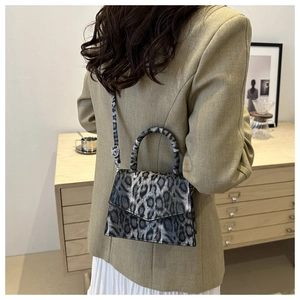 Detail of silver-tone adjustment buckle and reinforced handle on leopard print bag