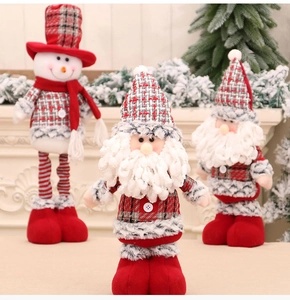 Close-up of plush Santa and Snowman dolls with fireplace and Christmas tree background