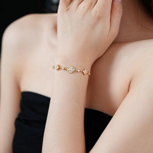 Close-up of gold-plated clover bracelet featuring sparkling zircon flower charms for women