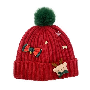 Red Christmas knit beanie with a green pompom, festive bow and cute reindeer doll