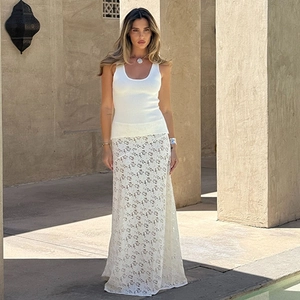 Close-up of white lace skirt and knit top on a model in sunlight, fashion detail view