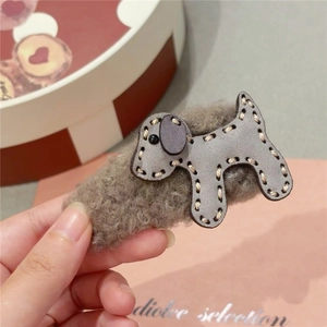 Detail of plush grey puppy hair claw clip with cozy faux fur and beige stitching detail