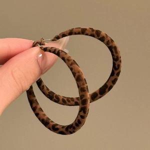 Close-up of leopard print acrylic C-shaped hoop earrings with brown flocking texture