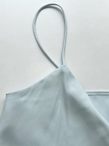 Close-up of light blue silk top showing fine spaghetti straps and precise stitching detail